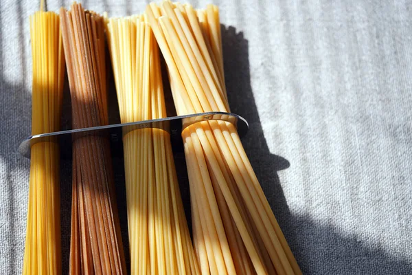 A measure of spaghetti with pasta in it lying on a canvas. Close up.  Cooking. Metal kitchen tools. Batch measurement. Kitchenware