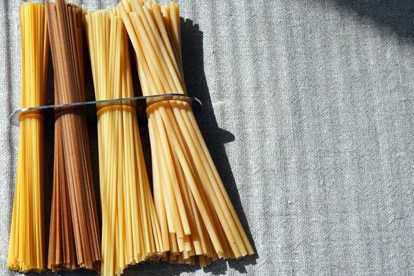 A measure of spaghetti with pasta in it lying on a canvas. Close up.  Cooking. Metal kitchen tools. Batch measurement. Kitchenware