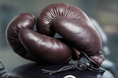 Kahverengi boks eldivenleri siyah arka plandaki bağcıklara asılıyor. Spor malzemeleri. Antrenman. Dövüş. Antrenman.                              
