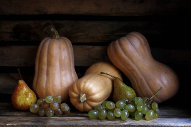 Sonbahar hala hayattır. Tahta kutuda balkabakları, armutlar, elmalar ve üzümler. Kırsal bir sonbahar hasadı. Koyu arkaplanda doğal ürünler.