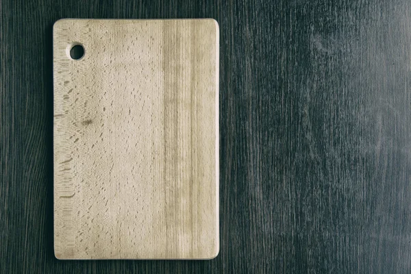 Koyu kahverengi ahşap masa arka plan üzerinde hafif sarı ahşap kesme kurulu yalan