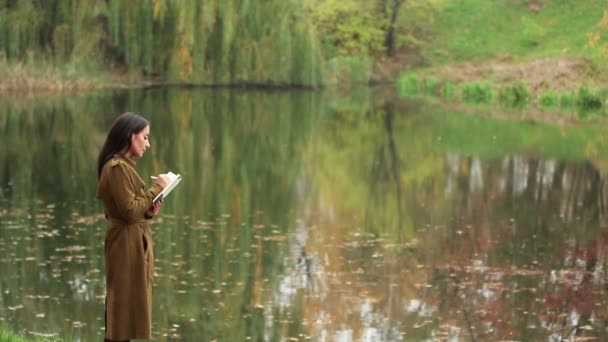 Joven Mujer Blanca Escribe Cuaderno Pie Junto Lago Paisaje Otoño — Vídeo de stock