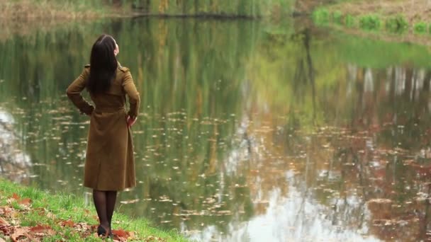 Νέος Slim Γυναίκα Weared Στο Καφετί Παλτό Στέκεται Στη Λίμνη — Αρχείο Βίντεο