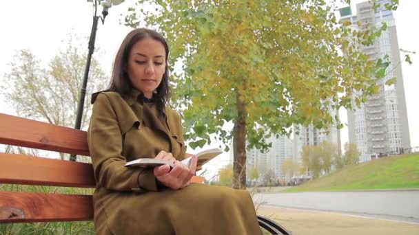 Menina Bonita Vestida Casaco Cáqui Senta Banco Parque Outono Livro — Vídeo de Stock