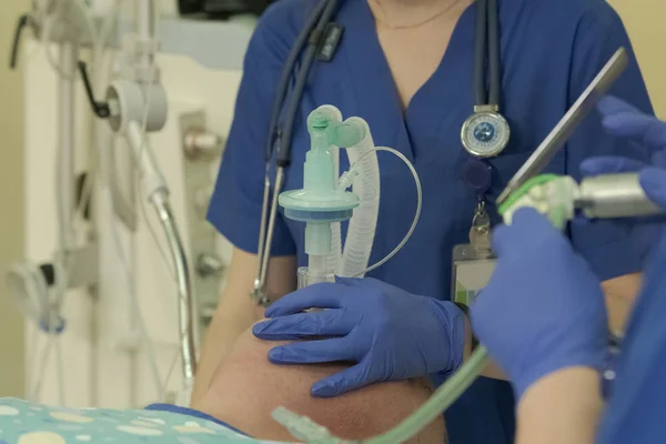 Yardımcısı ile yüzüne bir maske iterek cerrahi ön plan yakın çekim bir entübasyon araç hazırlar önce anestezi uzmanı bir hastaya genel anestezi olur