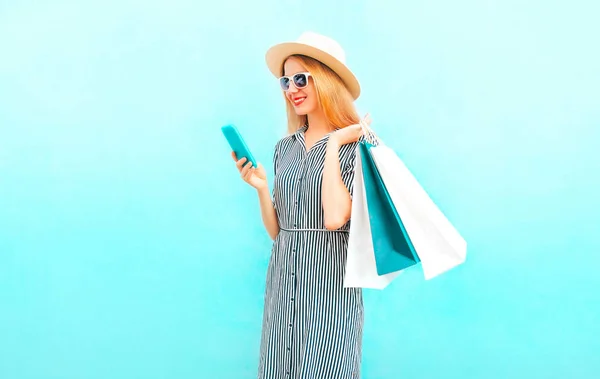 スマート フォン 青い背景の縞模様のドレスのショッピング バッグでファッション幸せ笑顔の女性 — ストック写真
