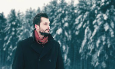 Moda kış günü, görüntüsü uzakta karlı orman ağaçları arka plan üzerinde yürüyen esmer adam sakallı