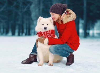 Mutlu bakmakta genç kadın beyaz kucaklayan Samoyed köpek kış günü