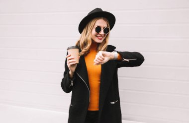 Şık gülümseyen kadın portre ses komutu yazmak veya kahve fincanı şehir sokak üzerinde tutarak arama alır kullanarak akıllı saatle duvar arka plan gri