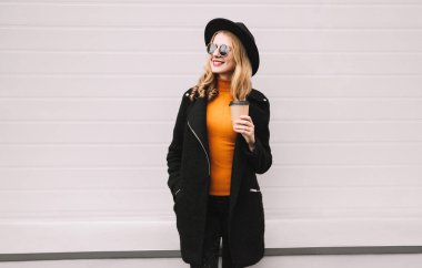 Mola zamanı! Kahve Kupası uzağa gri duvar arka plan üzerinde şehirde seyir ile güzel gülümseyen genç kadın