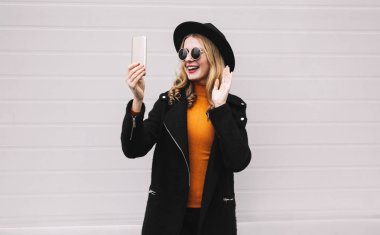 İnsanlar, teknoloji ve iletişim kavramı - gülümseyen kadın video aramasý veya alarak selfie yanında smartphone gri duvar arka plan üzerinde olması