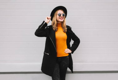 Şık gülümseyen genç kadın şehir gri duvar arka plan üzerinde poz