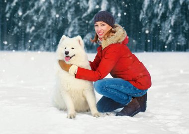 Birlikte kış gününde karlı parkta yürüyen kadın ve beyaz Samoyed köpek