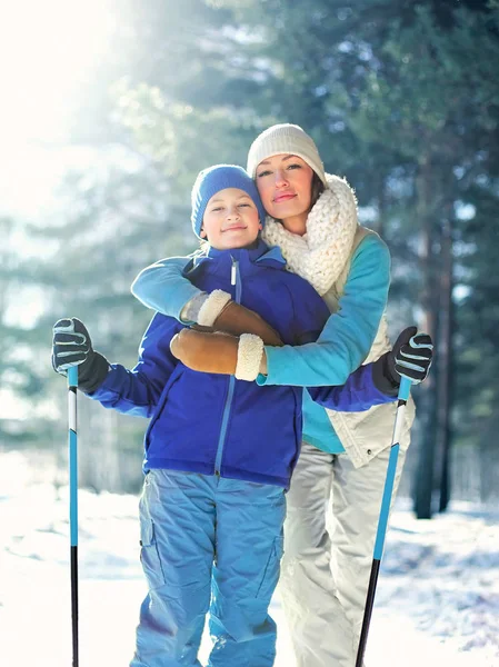 肖像快乐微笑的母亲拥抱孩子与滑雪在冬天寒冷的森林 — 图库照片