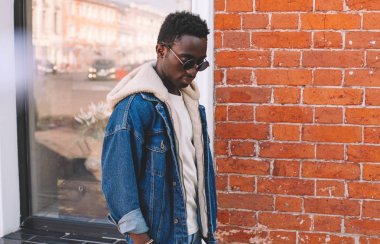 Afrika adam şehirde sokak, tuğla duvar arka plan dokulu kot ceket moda