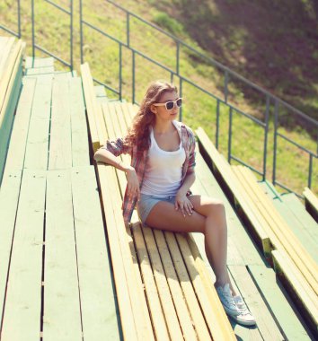 Güneşli yaz günü şehir parkta bankta oturan genç kız