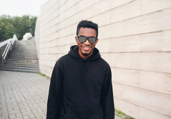 Ritratto felice uomo africano sorridente con cappuccio nero, occhiali da sole o — Foto Stock