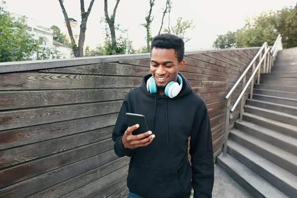 Portret szczęśliwy uśmiechający się afrykańskiego człowieka z telefonu, słuchawki słuchać — Zdjęcie stockowe