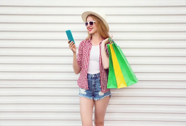 Glücklich lächelnde junge Frau mit Telefon, bunte Einkäufe in der Hand — Stockfoto