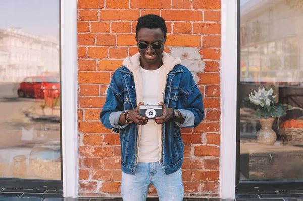 Felice sorridente africano uomo holding vintage film camera taking pic — Foto Stock