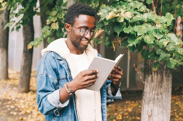 Portrait happy smiling african man reading book in autumn city p