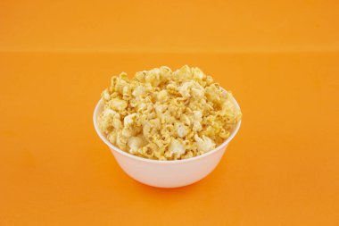 Turuncu arka plandaki kasede patlamış mısır. Yakın plan, yatay çerçeve.