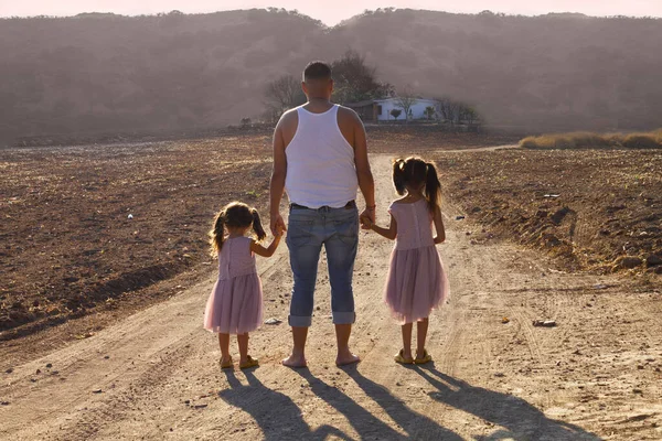 dad with daughters holding hands watching a landscape