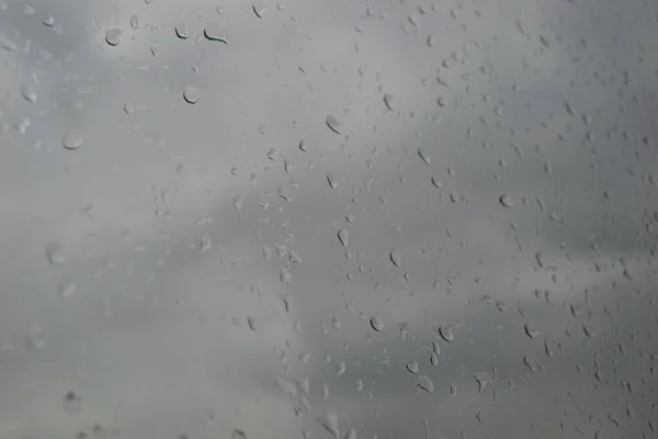 Gray sky through dirty glass with raindrops