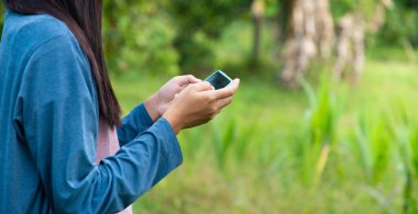 Çin bahçesinde cep telefonundan mesaj gönderen kadına yakın çekim.