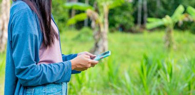 Çin bahçesinde cep telefonundan mesaj gönderen kadına yakın çekim.