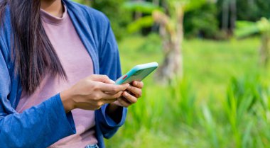 Çin bahçesinde cep telefonundan mesaj gönderen kadına yakın çekim.