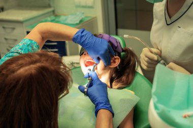 Mor eldivenli bir doktor klinikte küçük bir kıza ağrı kesici veriyor.