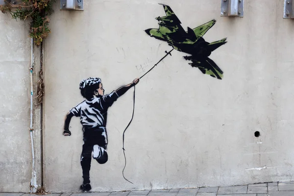 Banksy street art graffiti boy con aviones de combate cometa en Tel Aviv, Israel — Foto de Stock