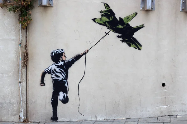 Banksy street art graffiti boy z latawcem myśliwskim w Tel Awiwie, Izrael Zdjęcie Stockowe