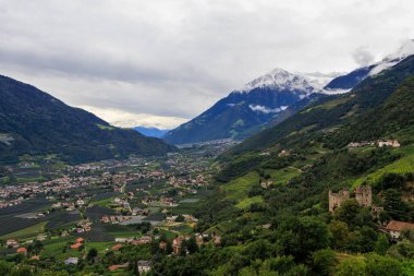 Schloss Brunnenburg kalesi, kar tepeli dağ zirvesi Cima di Tel (Zielspitze) ve Tirol 'den (Dorf Tirol) görülen vadi Etschtal ile Panorama, İtalya' nın güney kesiminde sonbaharda bulutlu bir günde