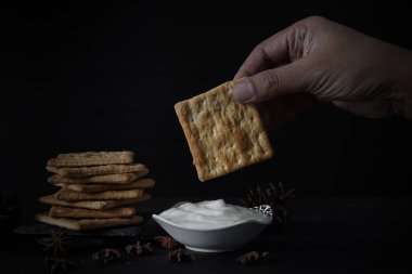 Beyaz yoğurtlu tuzlu kraker, siyah arka planda bir yığın kraker.