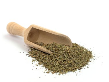 Beyaz arka planda baharat kepçesinde kurutulmuş fesleğen.