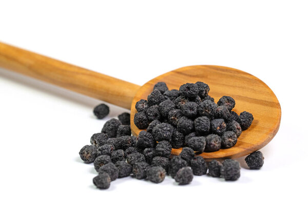 Dried Aronia berries, Aronia melanocarpa, on a wooden spoon