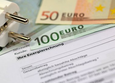 Enerji faturası, banknotlar ve elektrik prizi.