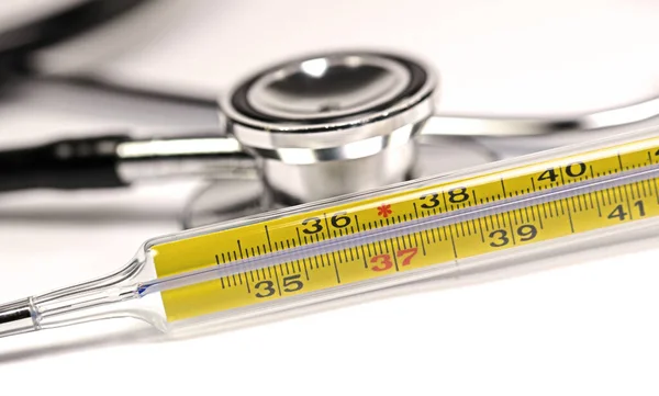 Clinical thermometer and stethoscope against white background