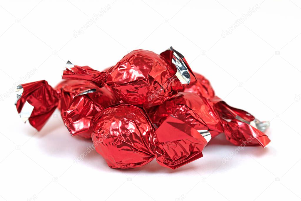 Chocolate sweets wrapped in aluminum foil against white background