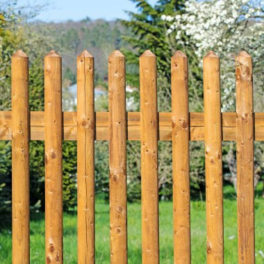 Fence field made of wooden slats in front of a garden clipart