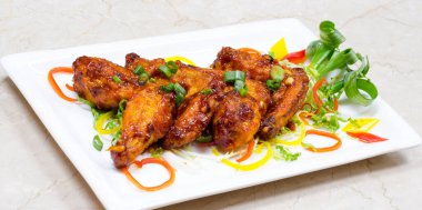 Tabağa konmuş kızarmış tavuk kanatları.