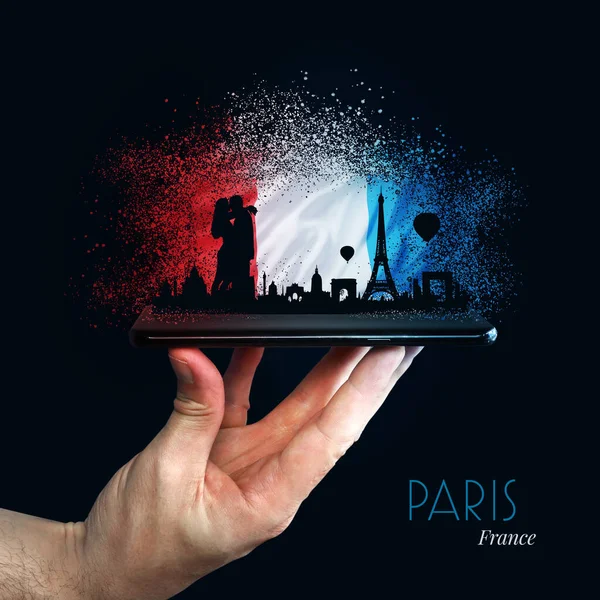 Paris (Fransa). Üzerinde renkli bir bayrak olan cep telefonu elinde. Skyline ve Çift önde. Seyahat, Turizm