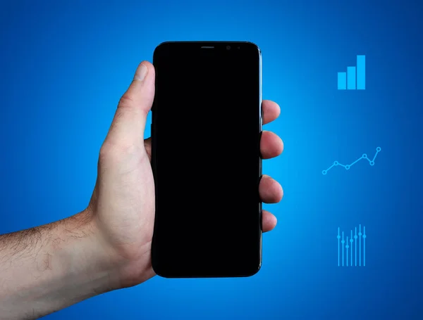 Elle tutulur telefon (cep telefonu) ve mevcut ekran. Mavi arkaplandaki çizelgeler. İş dünyası