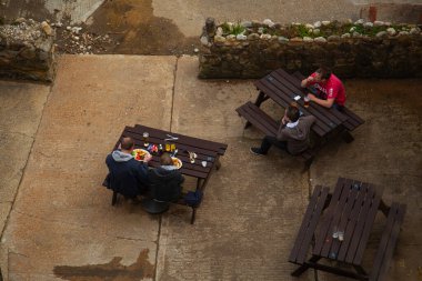 Wight Adası, 04 / 25 / 2010: Bir çift ve bir oğul yerel bir barda yemek yerken görülüyor. Açık havada, beton zemine yerleştirilmiş ahşap piknik masalarında oturmak sıradan bir atmosfer yaratıyor.. 