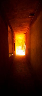 Eski bir taş binada dar ve karanlık bir koridor bulunan soyut bir görüntü. Işık, tünelin sonundaki perspektifin sonunda bir ışık ve iyi bir alan derinliği sağlar..