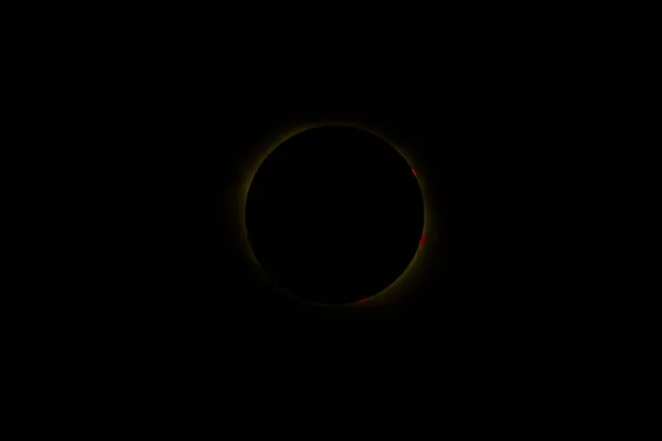 Image of a total solar eclipse taken with a telephoto lens. Massive solar flares and rim of light coming from corona are visible around the eclipse at totality. Image was captured at the moment of full eclipse in South Carolina during 2017 eclipse