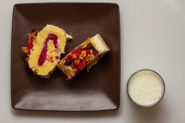 Ev yapımı iki dilim çikolatalı pastayı, lezzetli taze böğürtlenlerle doldurup vanilyalı krema kremalı cevizli cevizli ve çikolatalı cipsle bitirmeyi gösteren yakın plan. Sütle servis edilir.. 