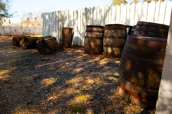 以殖民地美国生活方式为主题的抽象形象 图为威廉斯堡历史城区室外的木制原木 老式木桶和白色花园围栏 — 图库照片